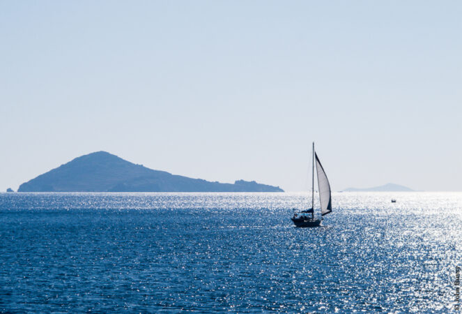 Autumn sun reflected on the sea with a yacht off the islet of Chiliomodi outside the harbour of Patmos. (Sept15)