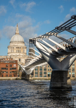 The low winter sun at the south end of the Millenium Bridge reflects brightly on its silver structure and contrasts with the warm stone of the cathedral and the dark, turbulent water. (Dec19)