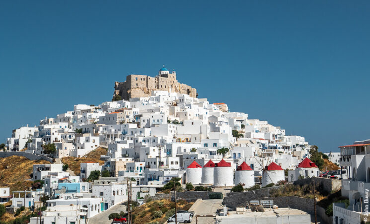 The Castle, and the blue dome of one of the churches, on top of the Chora, with the Platia and windmills below. (Jun22)