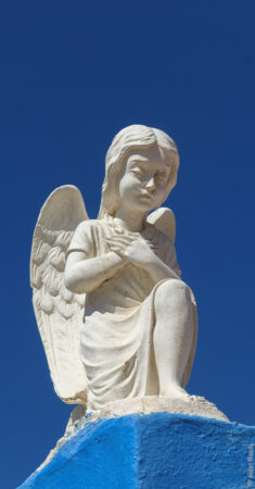 This angel was on the roof of a small roadside chapel near Fourni Town. {Oct24}